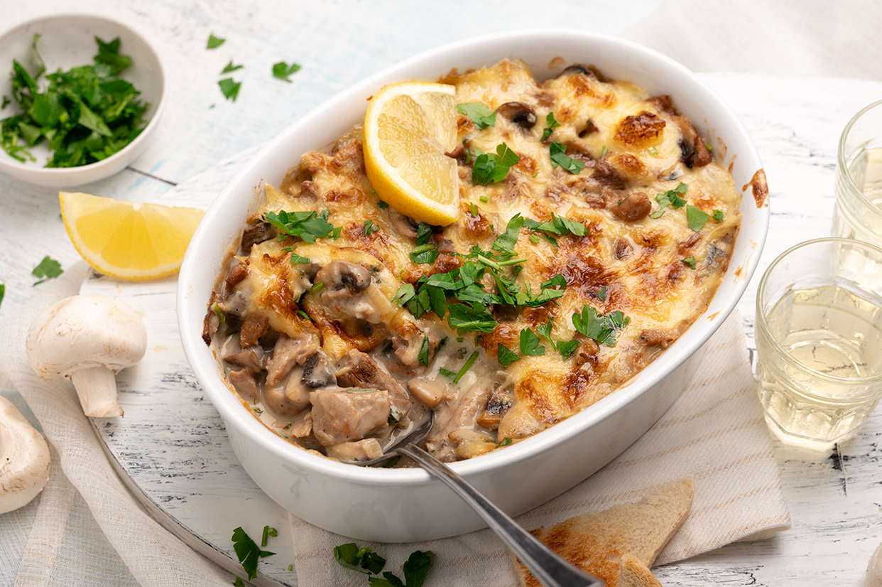 Veganes Ragout Fin in einer Auflaufform. Dazu Toastbrot und Zitrone.