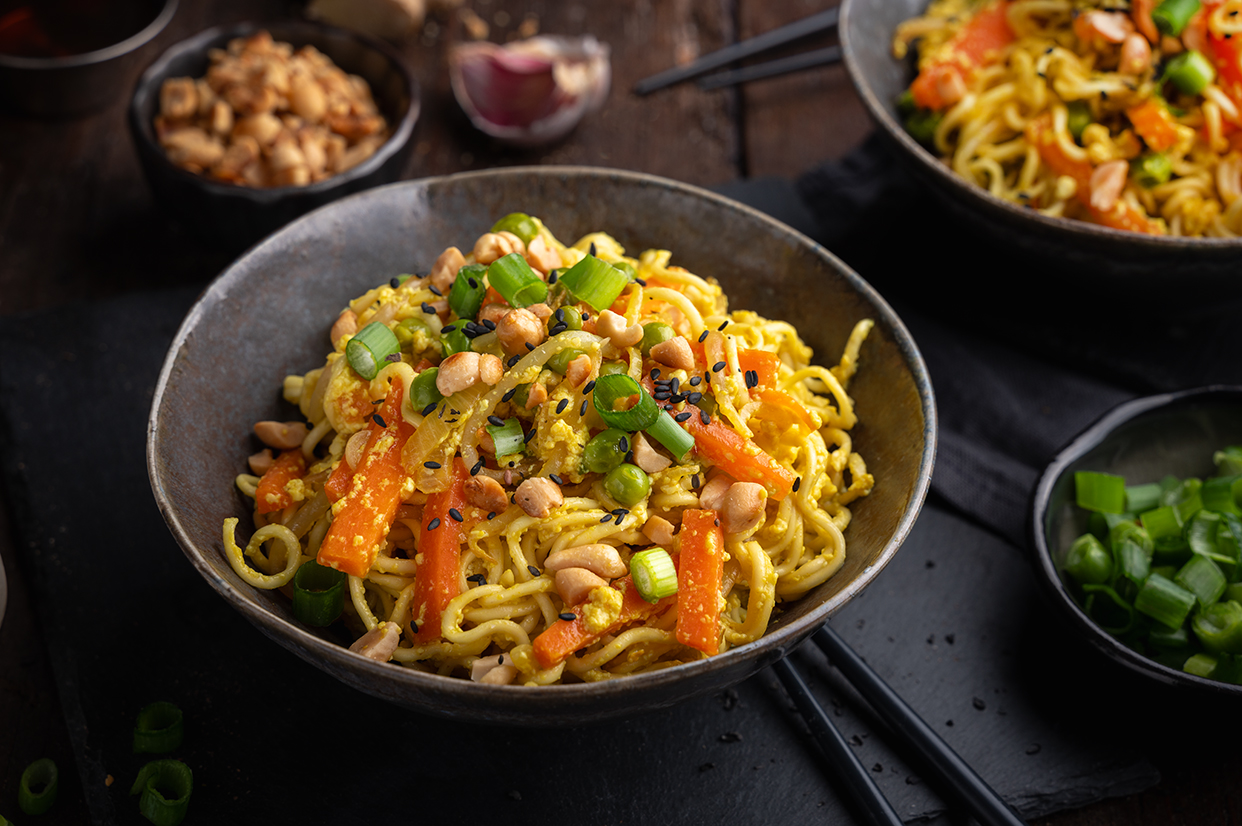 Gebratene Nudeln mit Seidentofu, Karotten, Erbsen, Mungobohnekeimlingen, gerösteten Erdnüssen, Frühlingszwiebeln und Sesam. vegan.